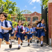 स्कूली बच्चे छुट्टी के बाद खुशी से बैग लेकर बाहर भागते हुए और पृष्ठभूमि में School Holiday 2026 लिखा बोर्ड
