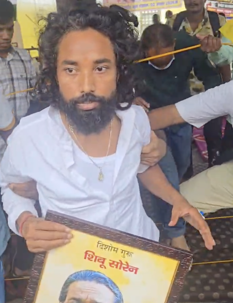 Student leader Devendra Nath Mahato on a stretcher holding a photo of Shibu Soren during the JPSC-JSSC protest march in Ranchi